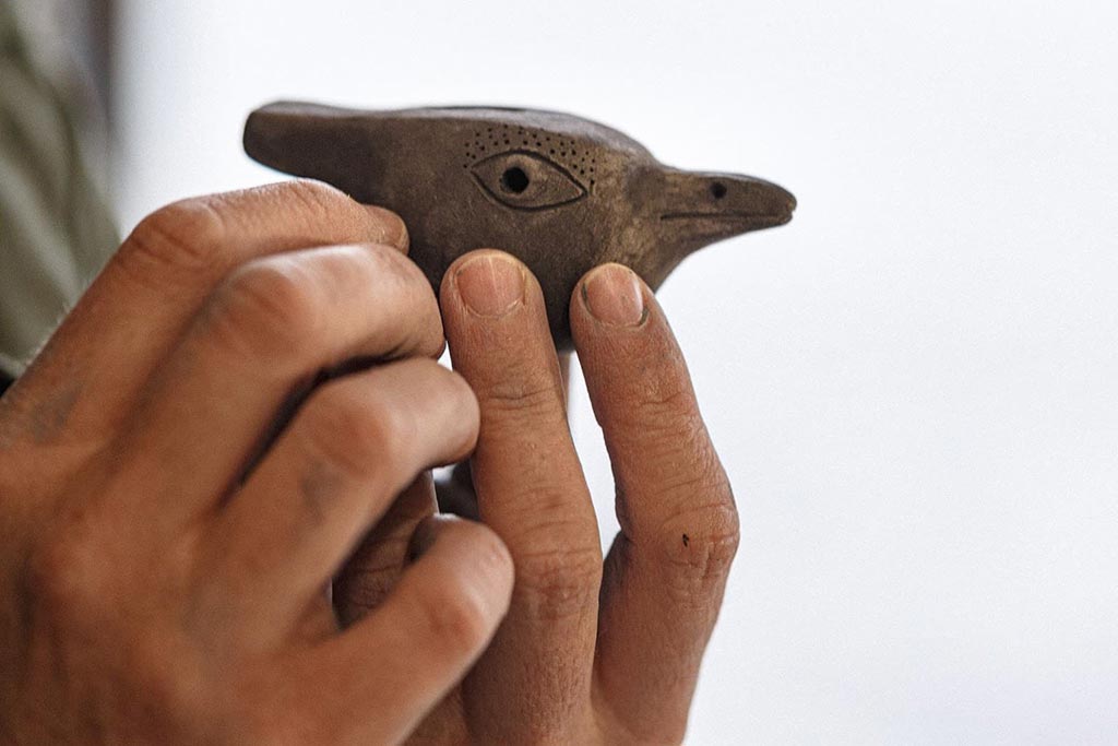 hands holding small clay bird